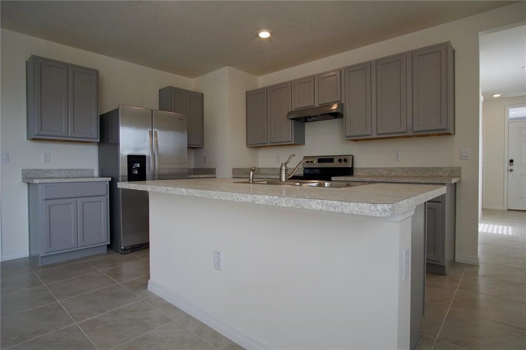 A kitchen features gray cabinets, stainless steel appliances, and a large central island with countertops — 1703 POST OAK DRIVE, DAVENPORT, FL