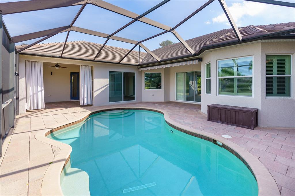 A swimming pool sits on a paved patio enclosed by a large screened-in lanai — 14717 BOWFIN TERRACE, BRADENTON, FL