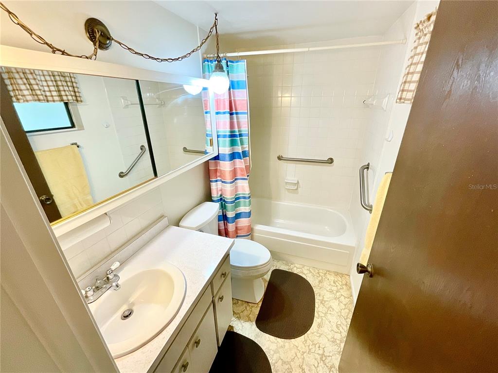 A bathroom features a vanity with a mirror, a toilet, and a tub-shower combination — 1980 TAHITIAN PLACE UNIT 15, DUNEDIN, FL
