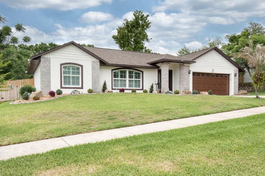 A single-story house with a white exterior, brick accents, and a brown garage door — 831 FORESTWOOD DR, MINNEOLA, FL
