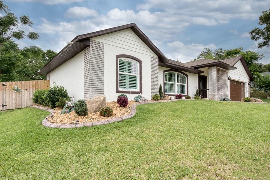 A single-story house with white stucco walls, brick accents, and a landscaped front yard — 831 FORESTWOOD DR, MINNEOLA, FL
