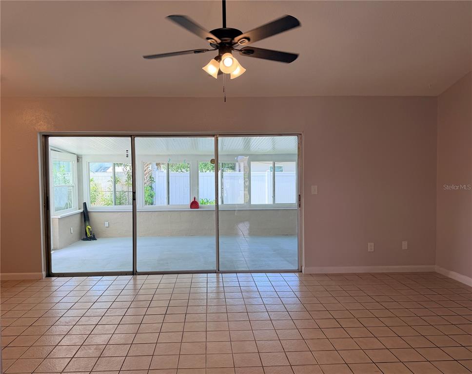 A room with tiled floors and a ceiling fan overlooks a screened-in patio — 208 FLAMINGO DRIVE, APOLLO BEACH, FL