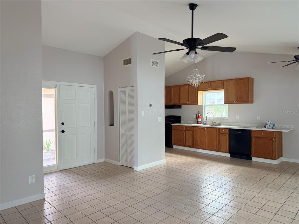 A kitchen and entryway feature tile flooring, wooden cabinets, and a vaulted ceiling — 208 FLAMINGO DRIVE, APOLLO BEACH, FL
