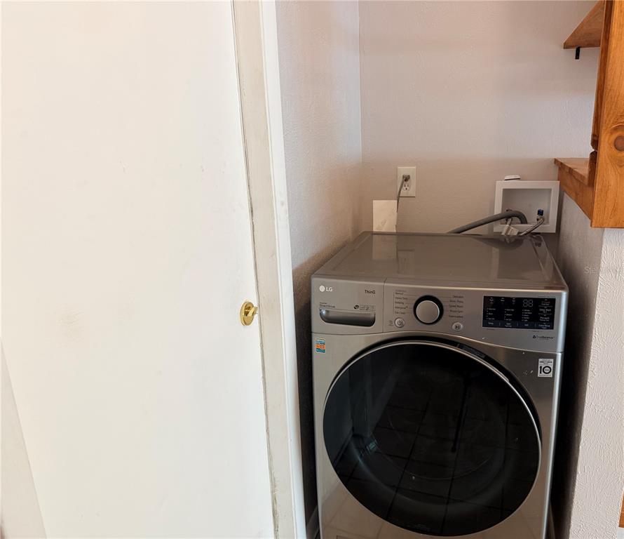 A silver LG front-load washing machine sits in a laundry closet with white walls — 208 FLAMINGO DRIVE, APOLLO BEACH, FL