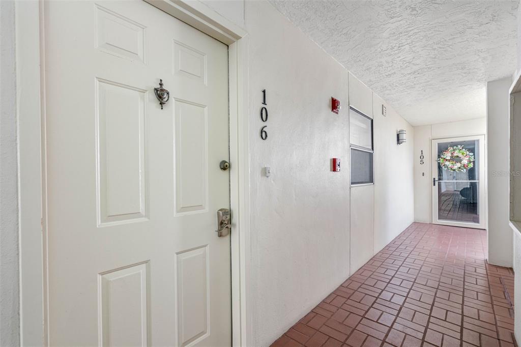 A hallway with tiled flooring leads to apartment doors numbered 106 and 105 — 7871 SAILBOAT KEY BOULEVARD S UNIT 106, SOUTH PASADENA, FL