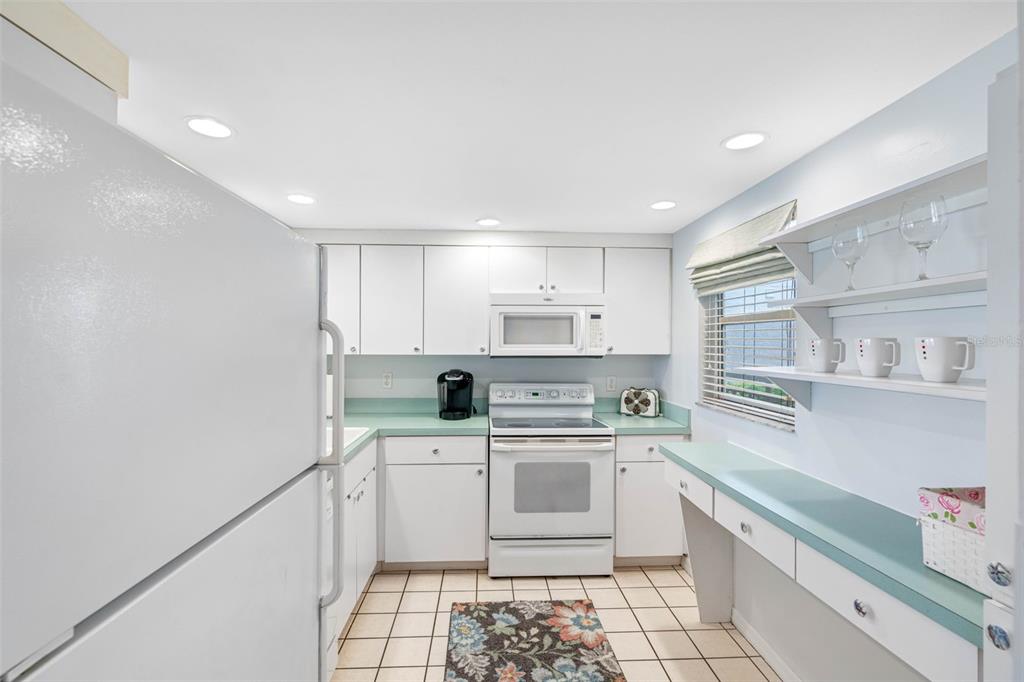 A kitchen with white cabinets, light green countertops, white appliances, and a tiled floor — 7871 SAILBOAT KEY BOULEVARD S UNIT 106, SOUTH PASADENA, FL