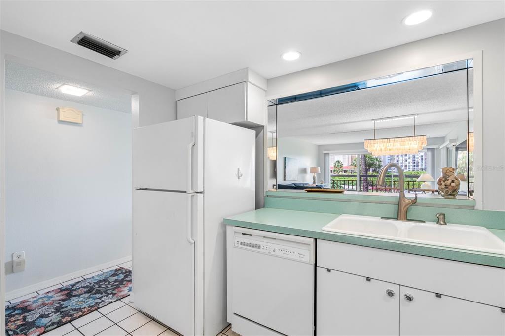 A kitchen features white appliances, a light green countertop, and a pass-through window to living — 7871 SAILBOAT KEY BOULEVARD S UNIT 106, SOUTH PASADENA, FL