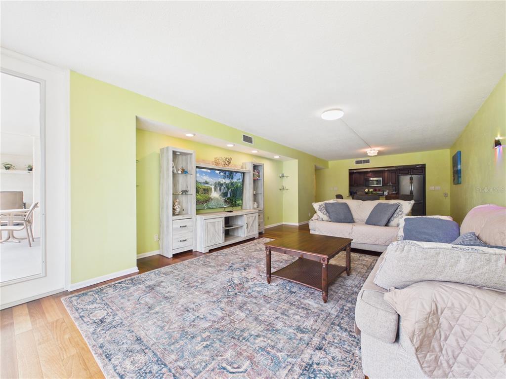 A living room with light green walls, a large area rug, and an entertainment center — 1400 GULF BOULEVARD UNIT 212, CLEARWATER BEACH, FL