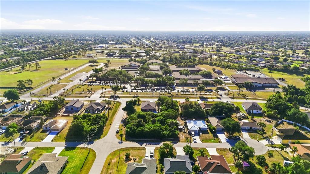 An aerial view shows a suburban neighborhood with houses, streets, and a large school complex — 109 SIDNEY COURT, ROTONDA WEST, FL
