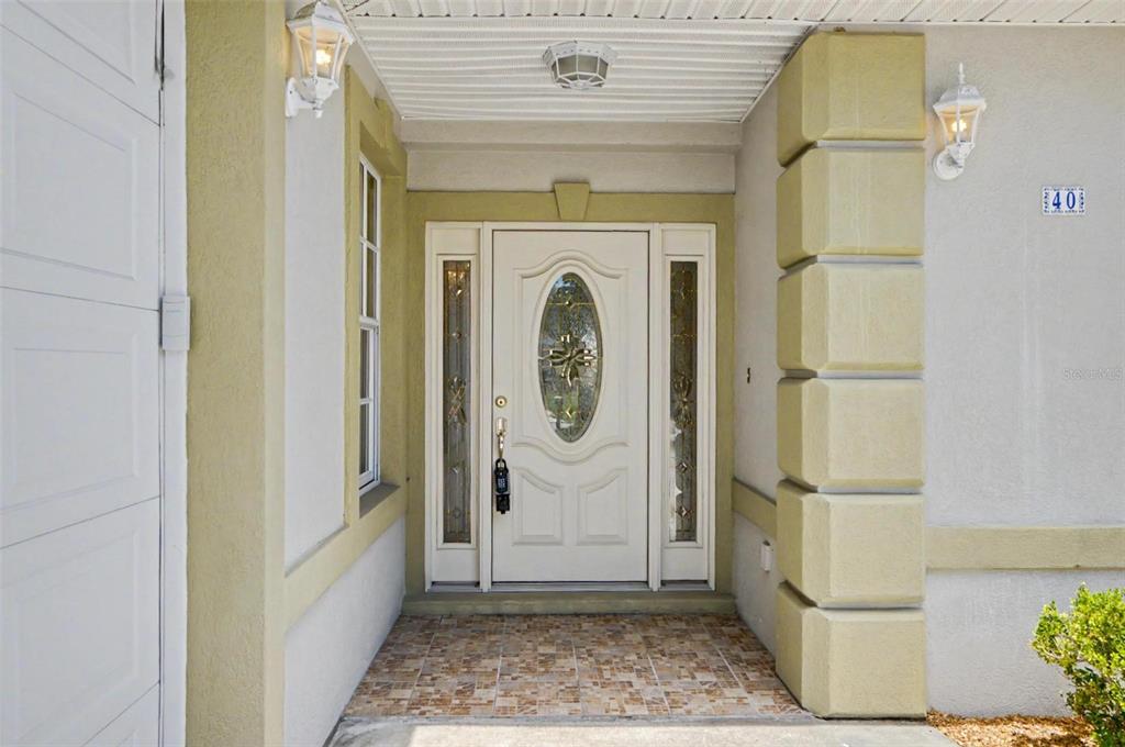 A front entrance features a white door with a glass oval insert and tiled flooring — 40 COLUMBIA LANE, PALM COAST, FL
