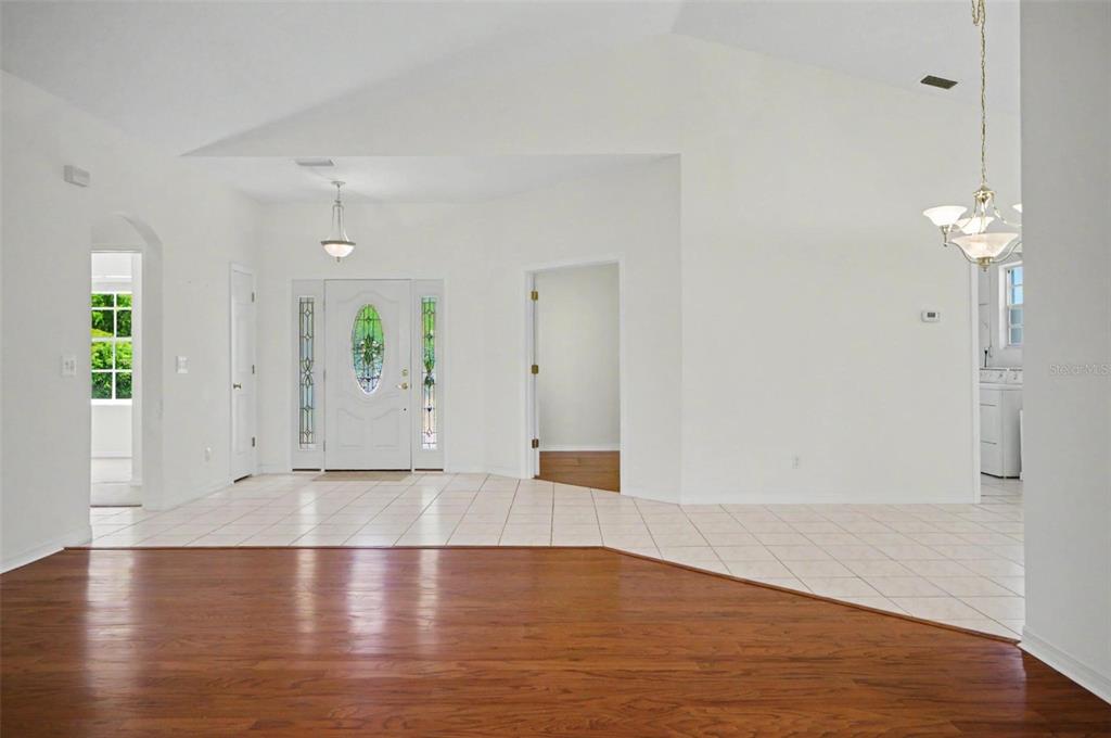A bright entryway features white walls, tiled flooring, a front door, and hardwood flooring — 40 COLUMBIA LANE, PALM COAST, FL