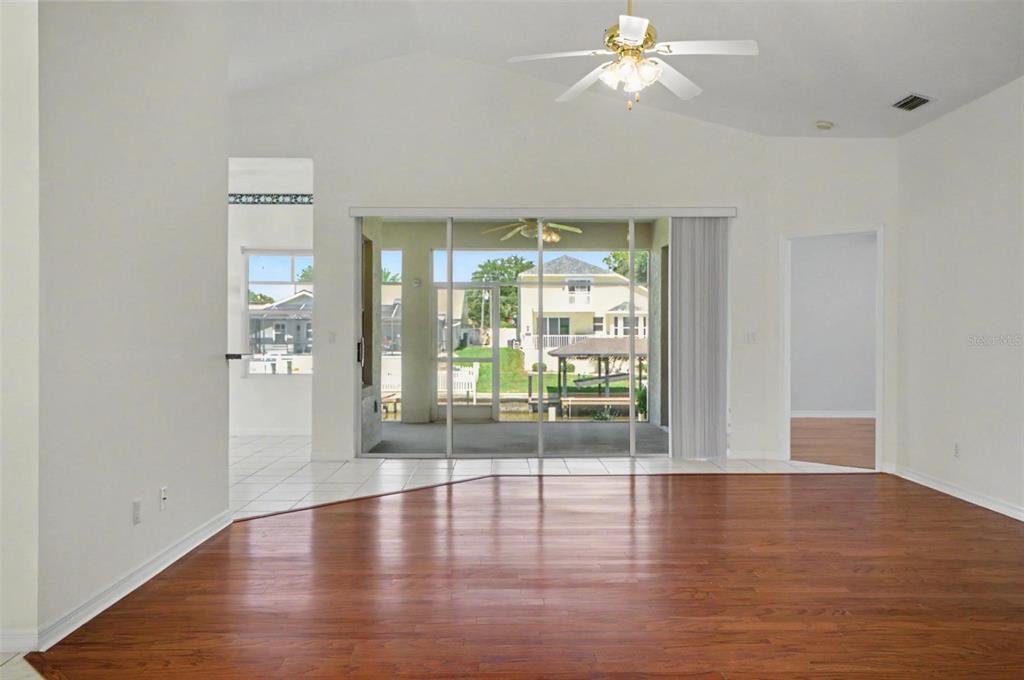 A living room with hardwood floors, white walls, a ceiling fan, and sliding glass doors — 40 COLUMBIA LANE, PALM COAST, FL