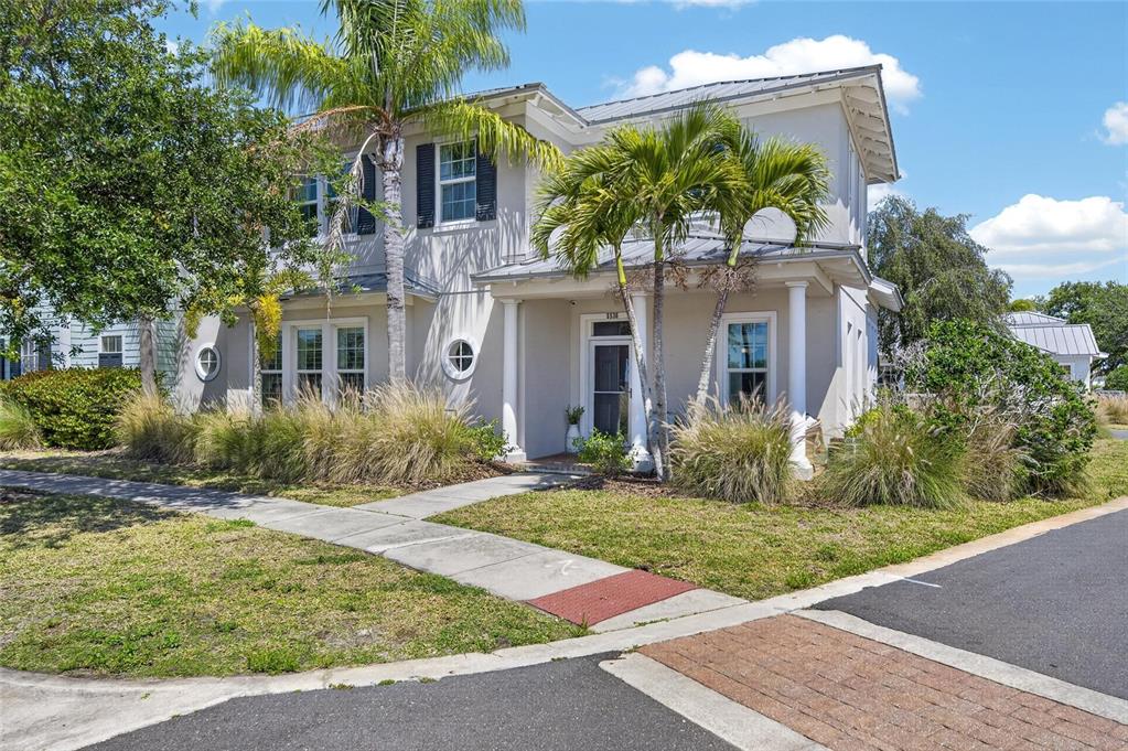 A two-story light-colored house features a front porch with columns and palm trees — 5536 LUMINAR POINTE LANE, APOLLO BEACH, FL