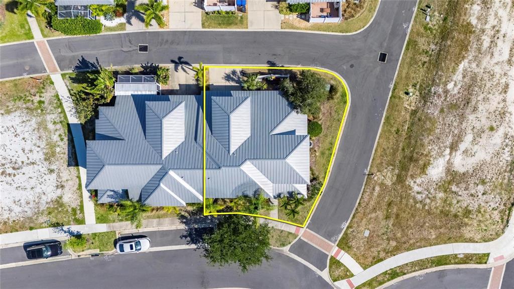 An aerial view shows a residential duplex with a metal roof on a corner lot — 5536 LUMINAR POINTE LANE, APOLLO BEACH, FL