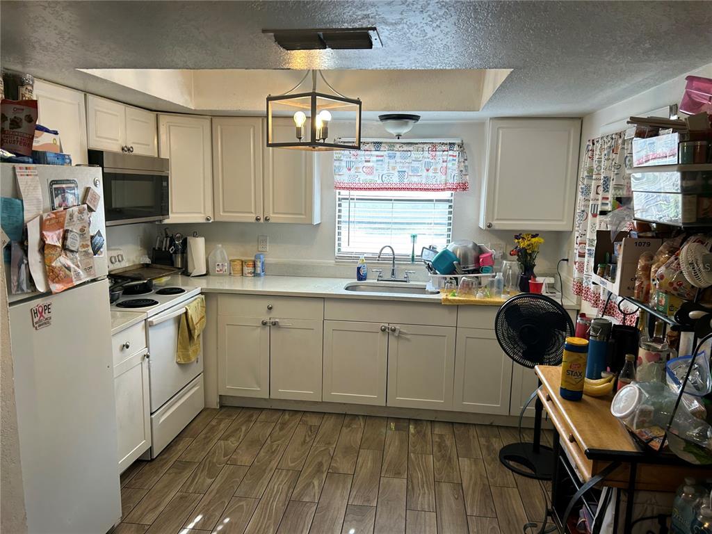A kitchen features white cabinets, stainless steel appliances, a window above the sink, and wood-look flooring — 6301 58TH STREET N UNIT 505, PINELLAS PARK, FL