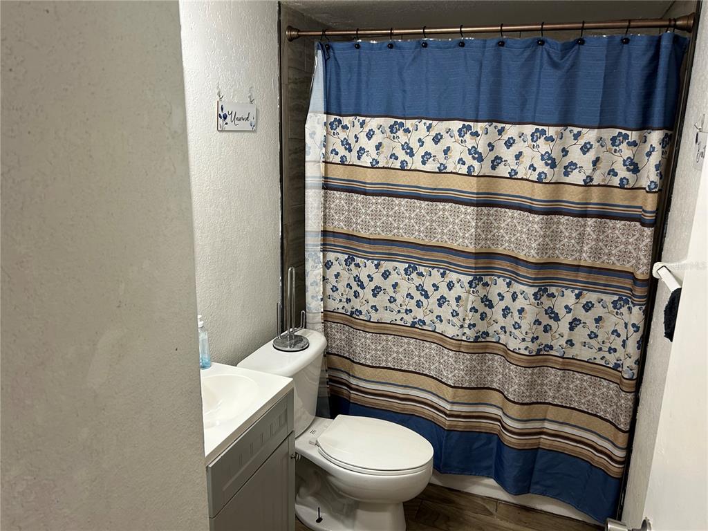 A bathroom features a vanity, a toilet, and a shower with a blue floral curtain — 6301 58TH STREET N UNIT 505, PINELLAS PARK, FL