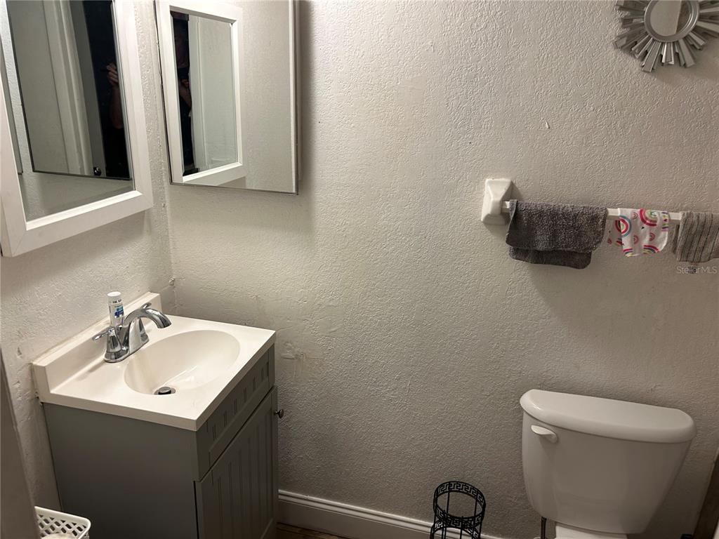 A bathroom featuring a gray vanity, white sink, toilet, and wall-mounted mirrors — 6301 58TH STREET N UNIT 505, PINELLAS PARK, FL