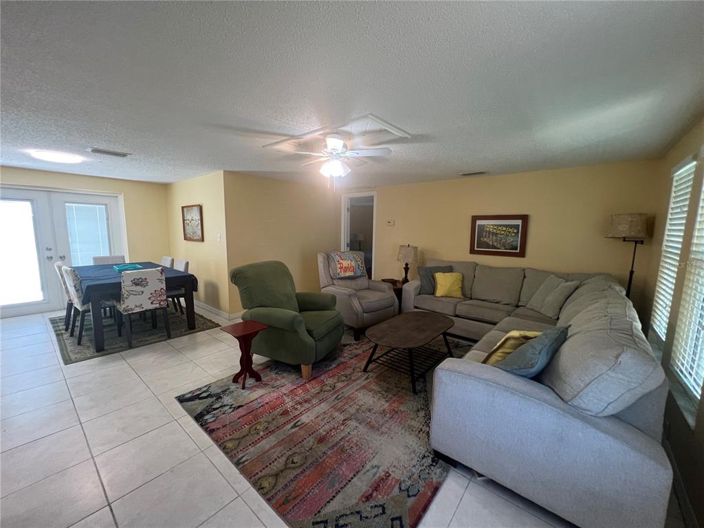 A living room and dining area with tile floors, a sectional sofa, and a rug — 650 HARTFORD DRIVE NW, PORT CHARLOTTE, FL