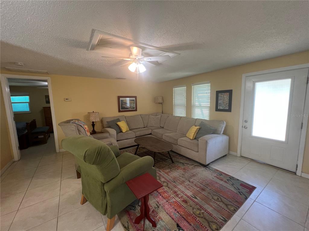 A living room features a sectional sofa, a green armchair, and tile flooring — 650 HARTFORD DRIVE NW, PORT CHARLOTTE, FL