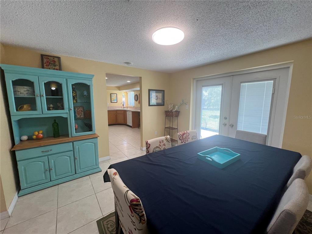 A dining room with a blue hutch, a dark-covered table, and a view into the kitchen — 650 HARTFORD DRIVE NW, PORT CHARLOTTE, FL