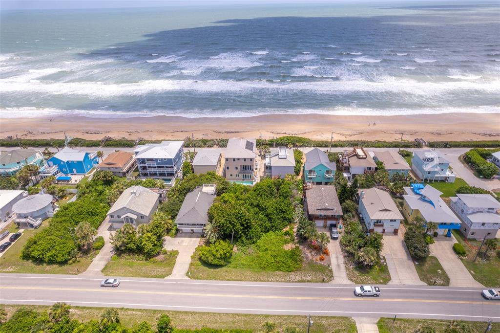 An aerial view shows a row of beach houses along the coast with a road — 6371 TURTLEMOUND ROAD, NEW SMYRNA BEACH, FL