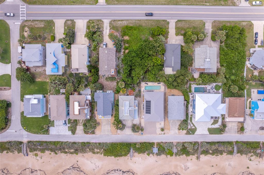 An aerial view shows a row of beachfront houses situated between a road and beach — 6371 TURTLEMOUND ROAD, NEW SMYRNA BEACH, FL