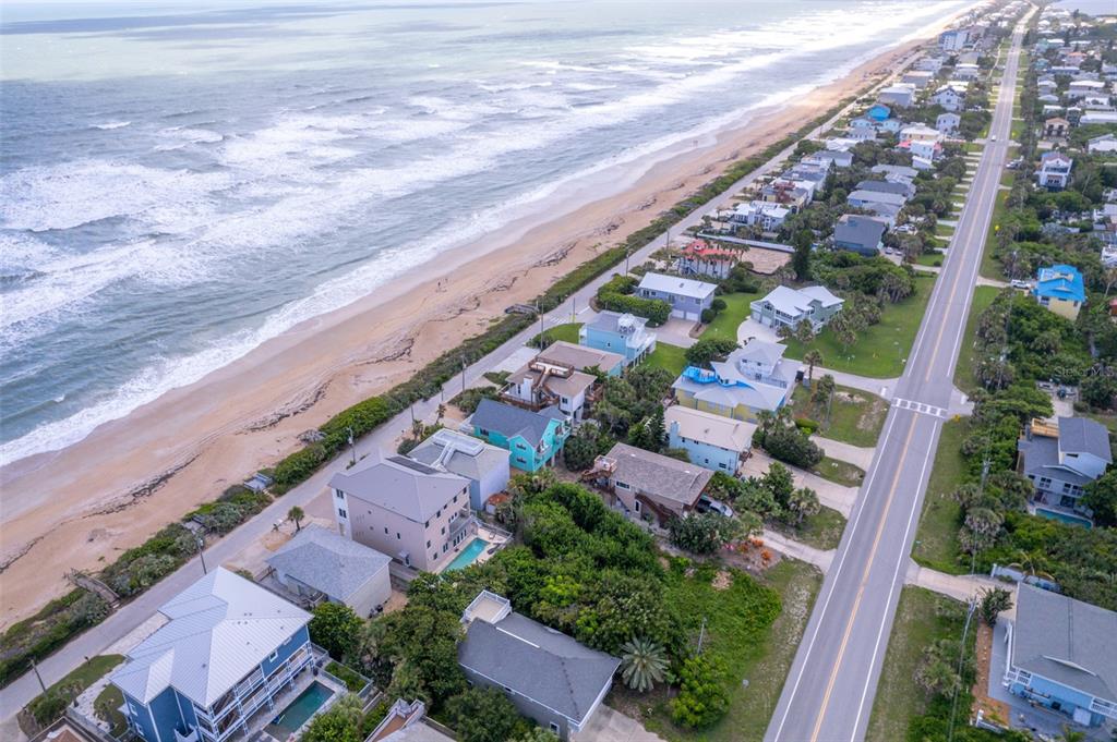 An aerial view shows a coastal road running parallel to a beach with residential houses — 6371 TURTLEMOUND ROAD, NEW SMYRNA BEACH, FL