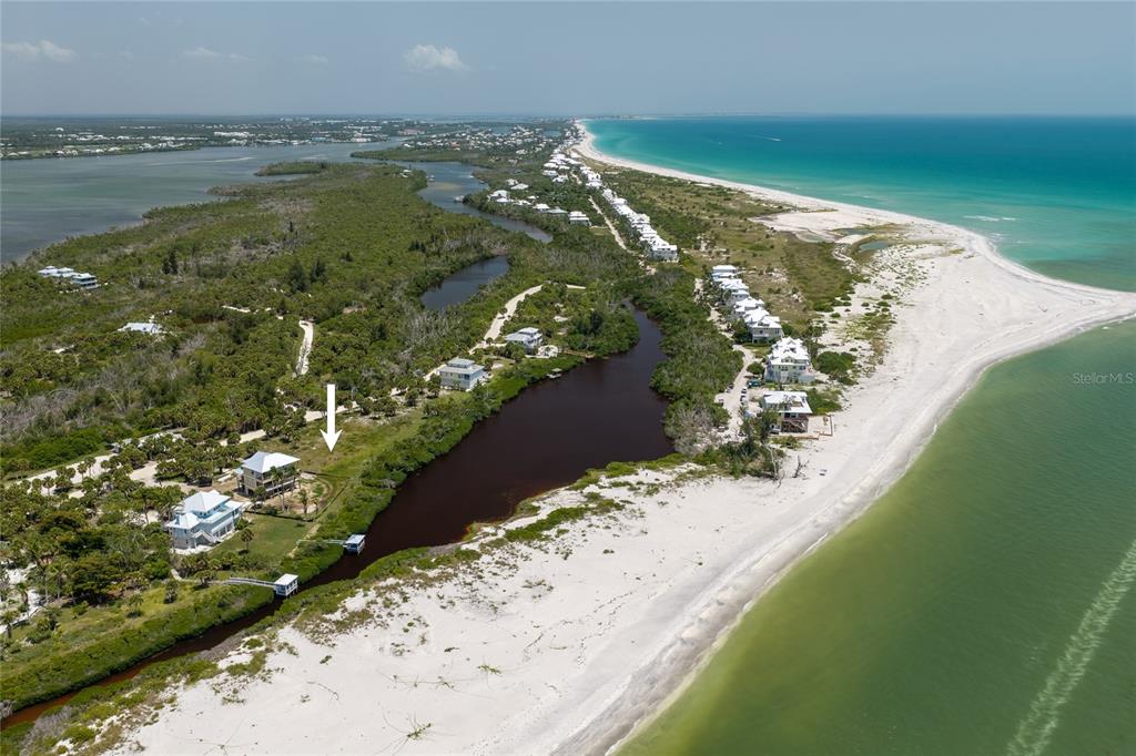 An aerial view shows a coastal property with a house, a small pond, and beach — 6060 RUM COVE DRIVE, PLACIDA, FL