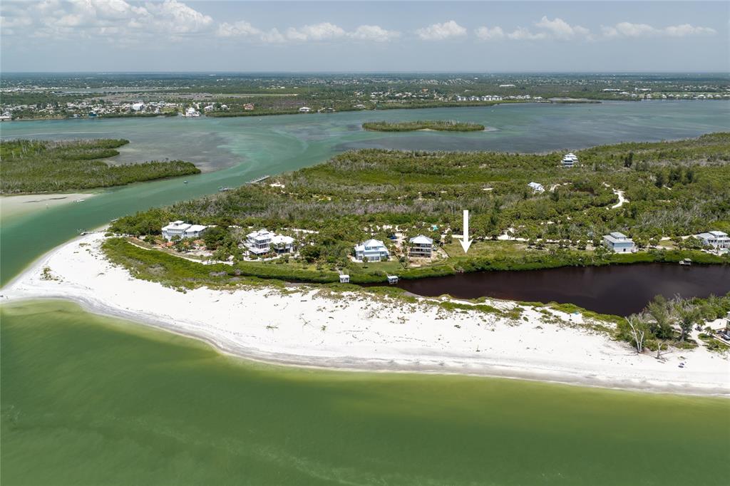An aerial view shows a white sandy beach, coastal vegetation, and several houses near water — 6060 RUM COVE DRIVE, PLACIDA, FL
