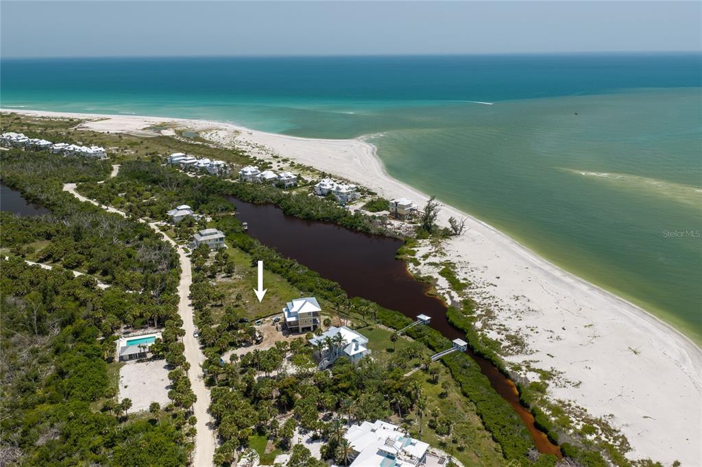 An aerial view shows a coastal house situated between a dark pond and the ocean — 6060 RUM COVE DRIVE, PLACIDA, FL
