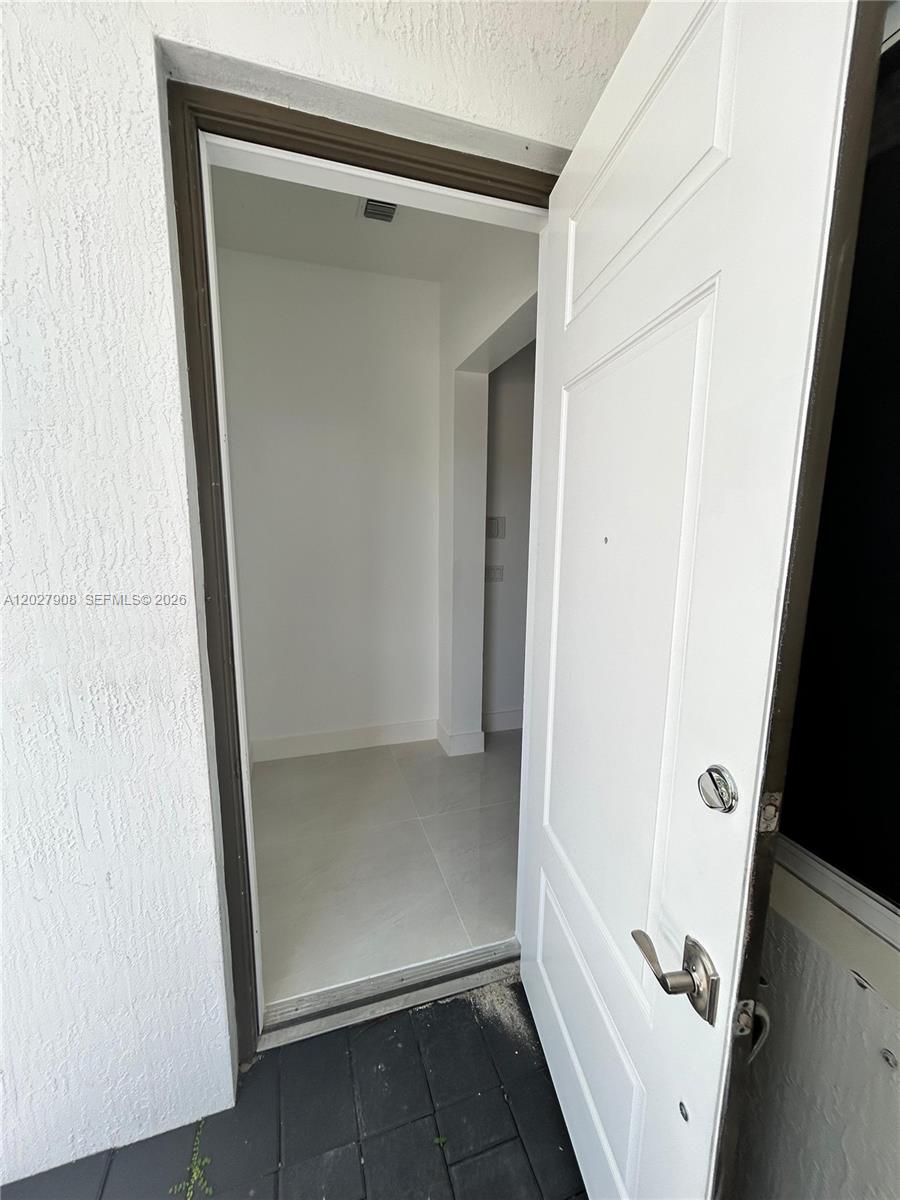 An open white door reveals a small entryway with light-colored tile flooring — MIAMI, FL