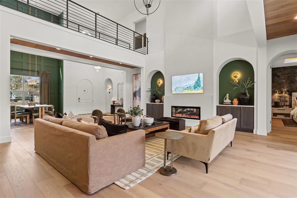 A spacious living room features a fireplace, arched built-ins, and a lofted balcony — 2080 LAKE MARKHAM ROAD, SANFORD, FL