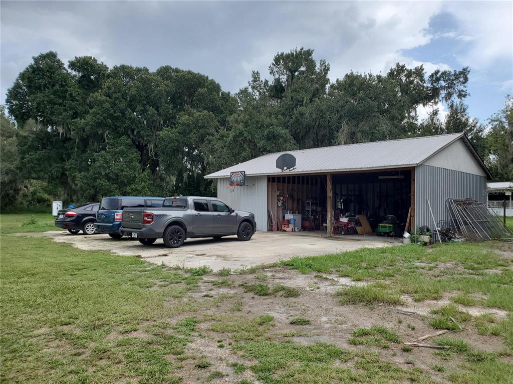 A gray metal workshop with an open bay sits next to three parked vehicles — 1662 HARVILL ROAD, WAUCHULA, FL