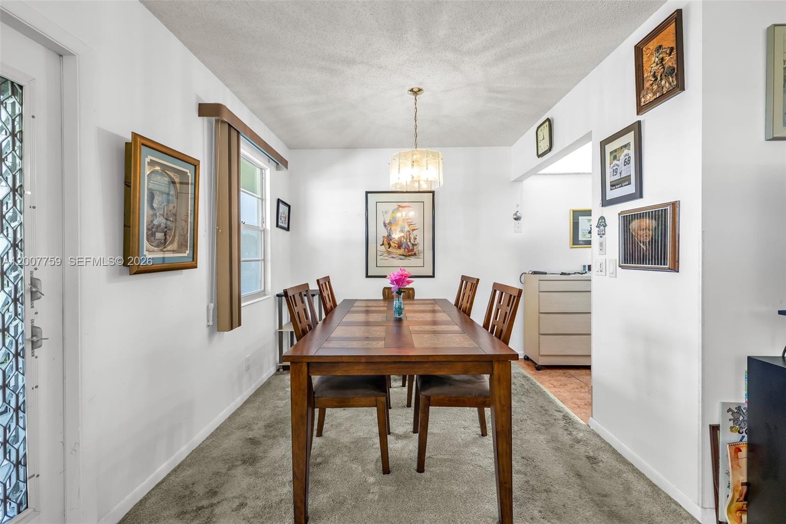 A dining room features a wooden table with six chairs, carpeted flooring, and wall art — 494 W Tilford  W # 494, Deerfield Beach FL 33442, DEERFIELD BEACH, FL