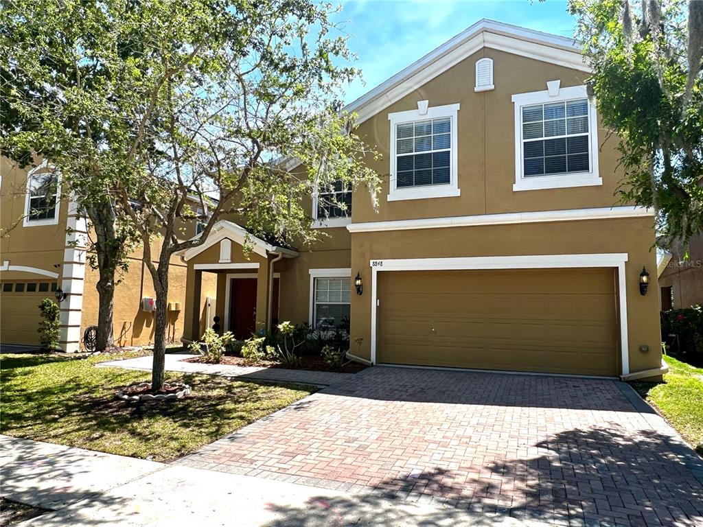 A two-story house with a tan stucco exterior, a two-car garage, and a paved driveway — 8848 CAMERON CREST DRIVE, TAMPA, FL