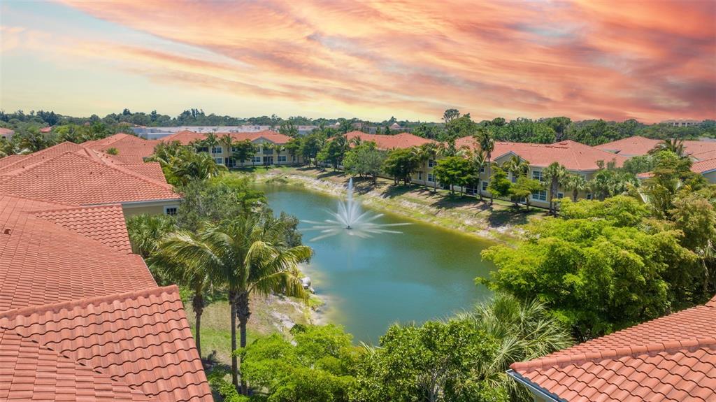 An aerial view of a pond with a fountain surrounded by apartment buildings with roofs — 89 NAVIGATION CIRCLE, OSPREY, FL