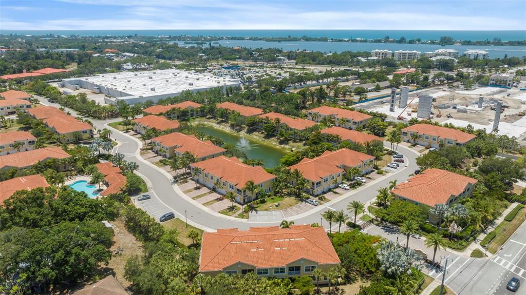 An aerial view shows a residential complex with orange-roofed buildings surrounding a central pond — 89 NAVIGATION CIRCLE, OSPREY, FL
