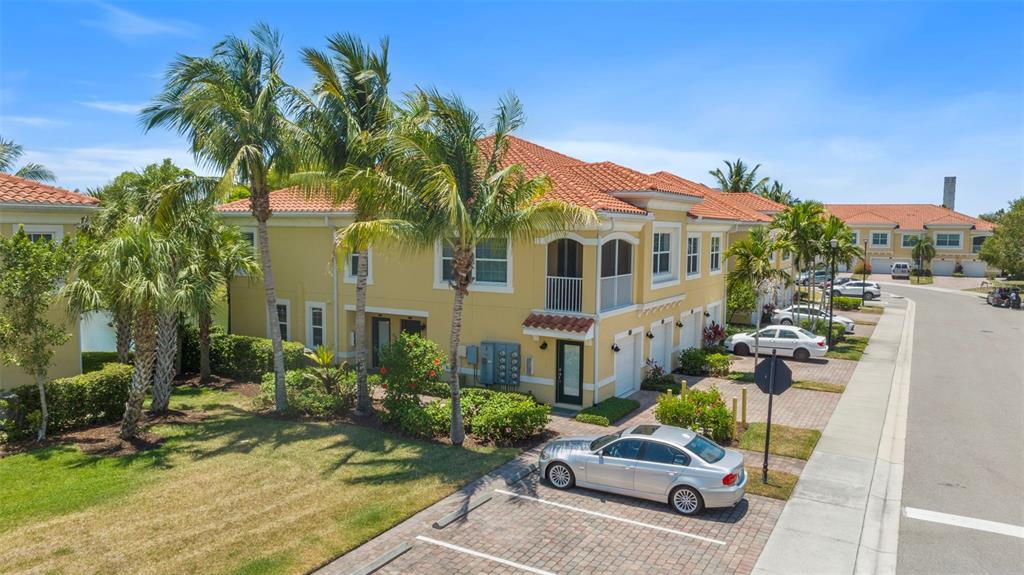 An exterior view of a two-story yellow townhouse with a tiled roof and parking spaces — 89 NAVIGATION CIRCLE, OSPREY, FL