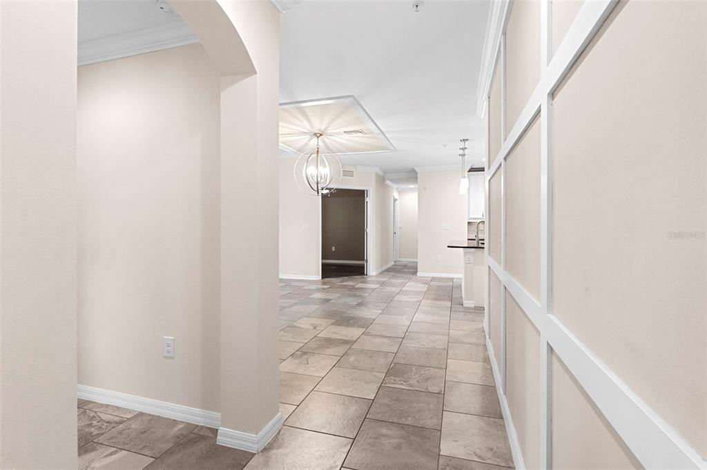 A hallway with tiled floors leads to an open dining area with a chandelier — 89 NAVIGATION CIRCLE, OSPREY, FL