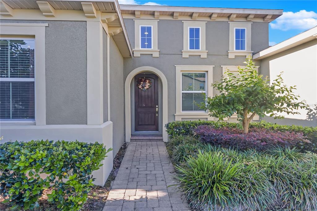 The exterior of a two-story house features a stone walkway leading to an arched doorway — 14246 CREEKBED CIRCLE, WINTER GARDEN, FL