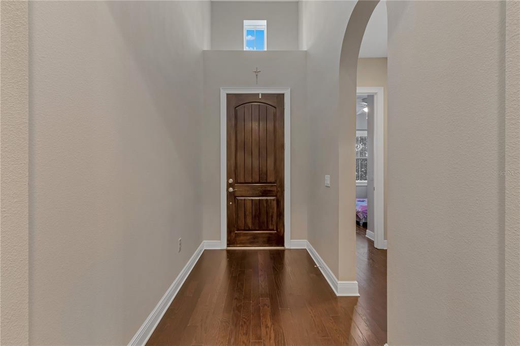 A foyer with hardwood floors, a dark wood front door, and a high ceiling — 14246 CREEKBED CIRCLE, WINTER GARDEN, FL