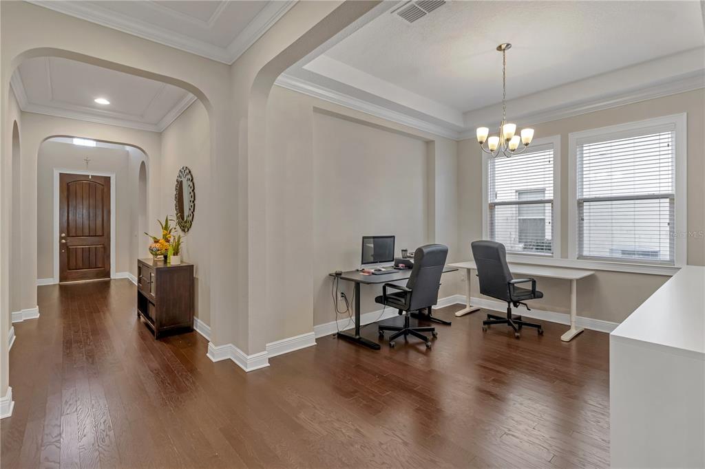 A home office area features two desks, dark wood flooring, and an adjacent hallway entrance — 14246 CREEKBED CIRCLE, WINTER GARDEN, FL