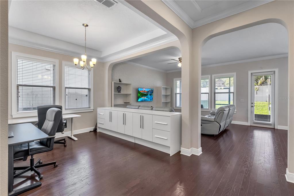 A home office area with dark wood floors opens into a living room with white cabinetry — 14246 CREEKBED CIRCLE, WINTER GARDEN, FL