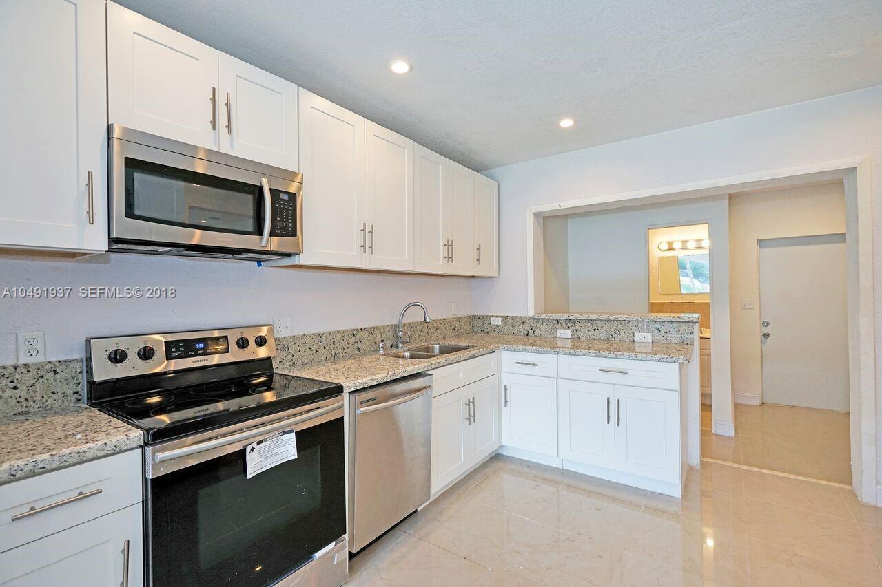 A kitchen features white cabinets, granite countertops, stainless steel appliances, and light tile flooring — 2000 SW 95th Terrace, Miramar FL 33025, MIRAMAR, FL