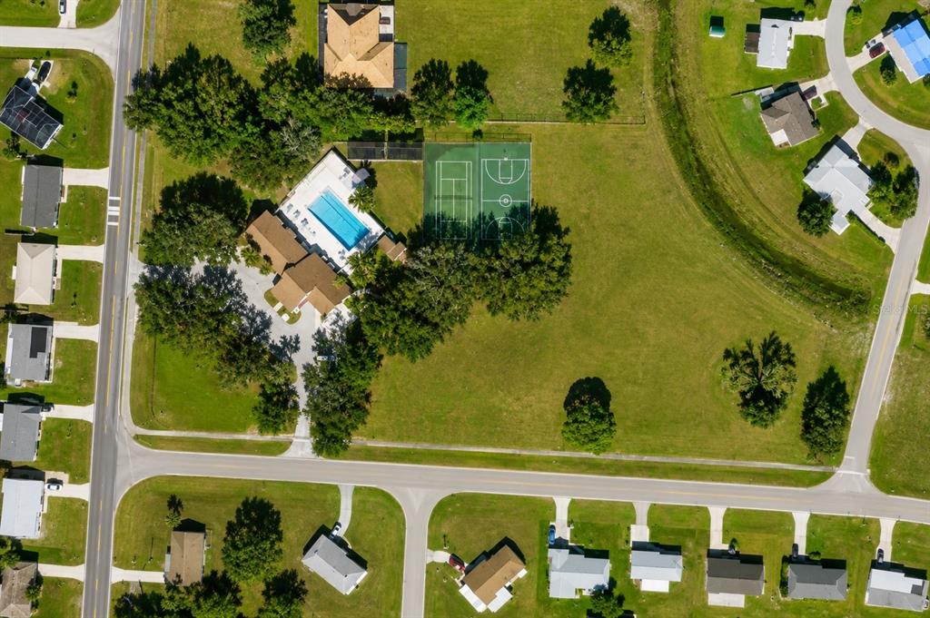 An aerial view shows a house with a swimming pool and sports courts on a lot — 3941 NEKOOSA STREET, NORTH PORT, FL