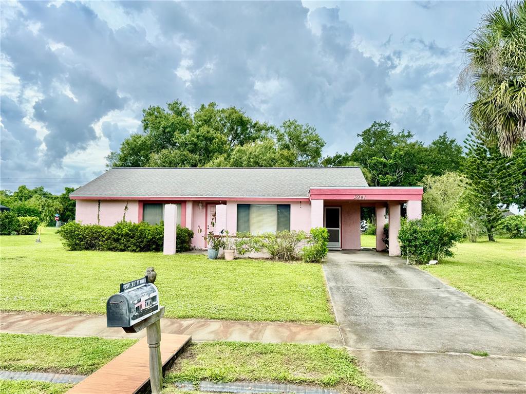 A single-story pink house with a concrete driveway and a front lawn under a cloudy sky — 3941 NEKOOSA STREET, NORTH PORT, FL