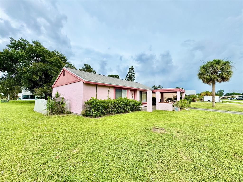 A pink, single-story house with a shingled roof sits on a large, grassy lot — 3941 NEKOOSA STREET, NORTH PORT, FL