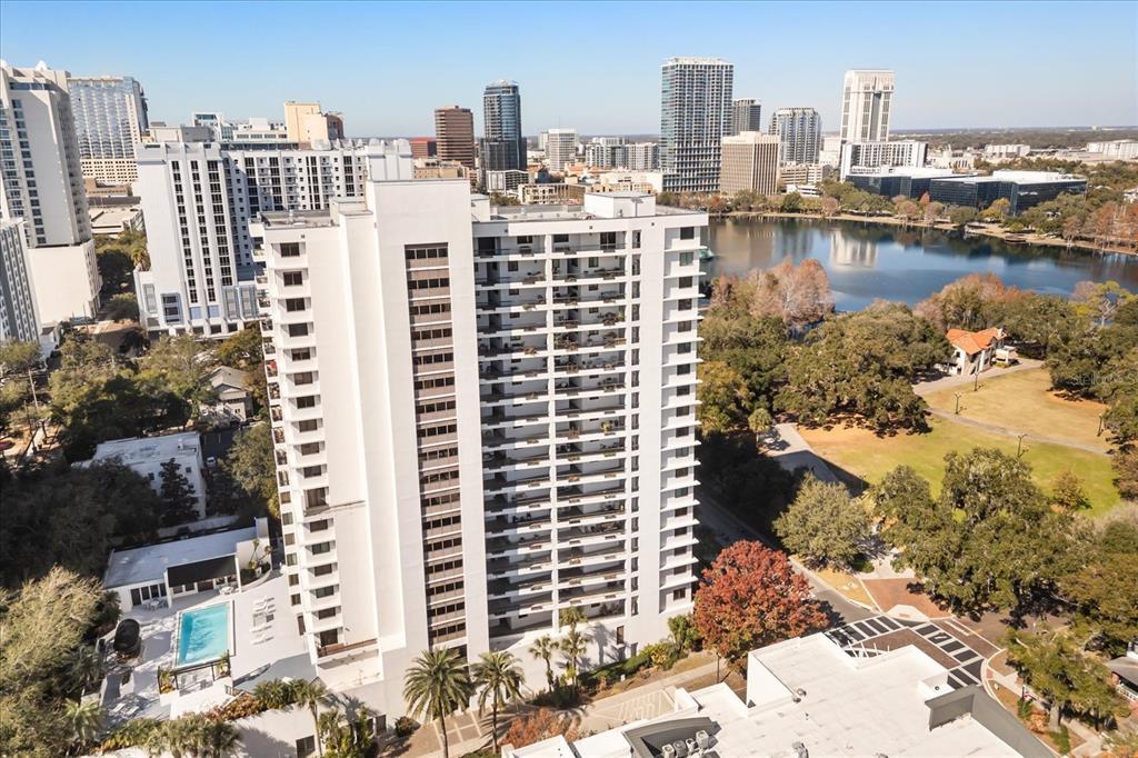 An aerial view shows a tall white apartment building next to a lake and park — 530 E CENTRAL BOULEVARD UNIT 1901, ORLANDO, FL