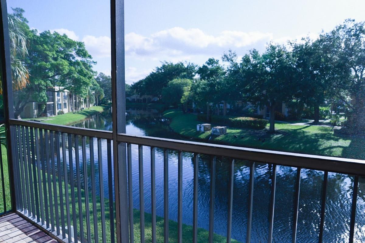 A view of a canal and trees from a screened-in balcony with metal railings — 428 Lakeview Drive # 201, Weston FL 33326, WESTON, FL