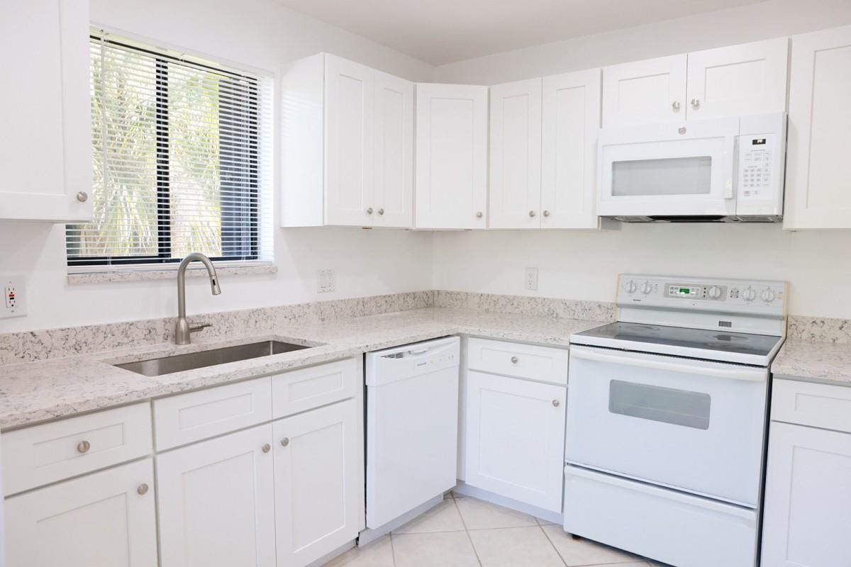 A kitchen with white cabinets, speckled countertops, a stainless steel sink, and white appliances — 428 Lakeview Drive # 201, Weston FL 33326, WESTON, FL